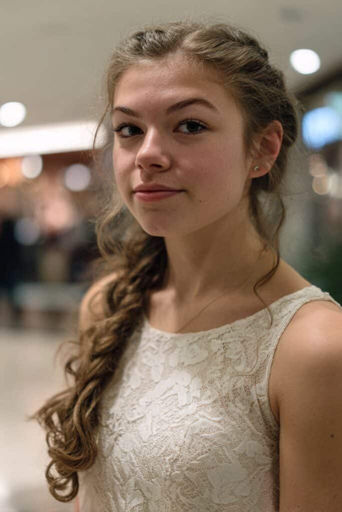 Teen girl with a cascading side braid prom hairstyle and curled ends.