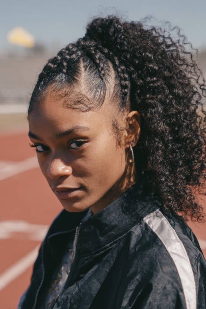 Black woman with cornrows flowing into a curly ponytail.