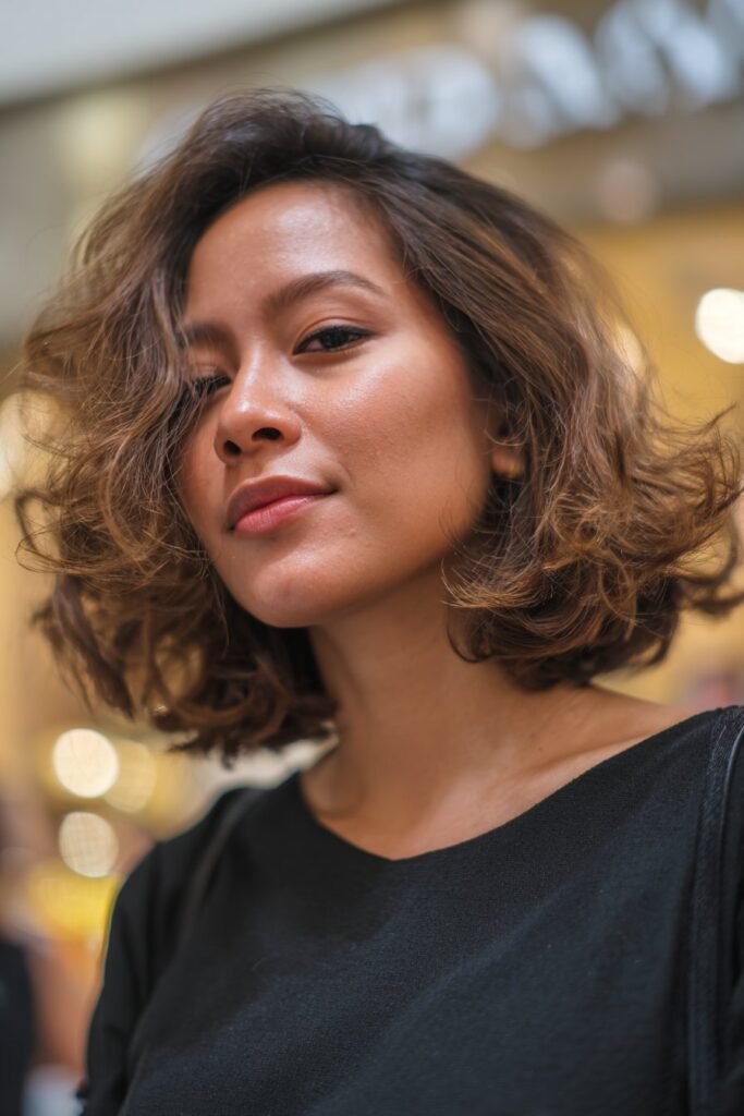 Woman with curly stacked bob and side swept fringe layers.
