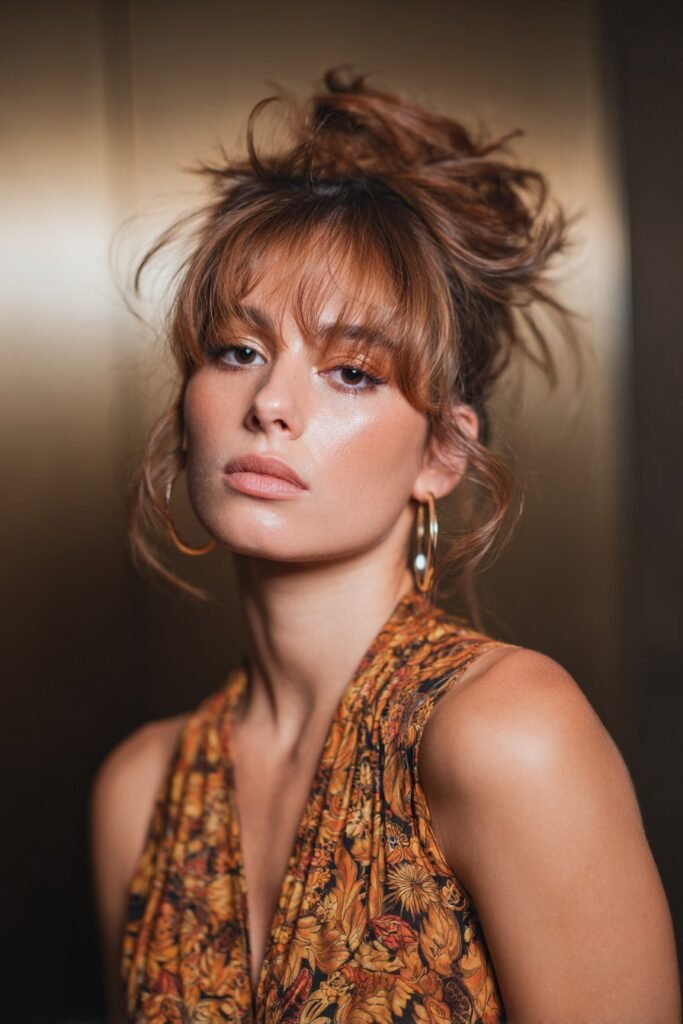 Feathered updo with loose tendrils framing the face.