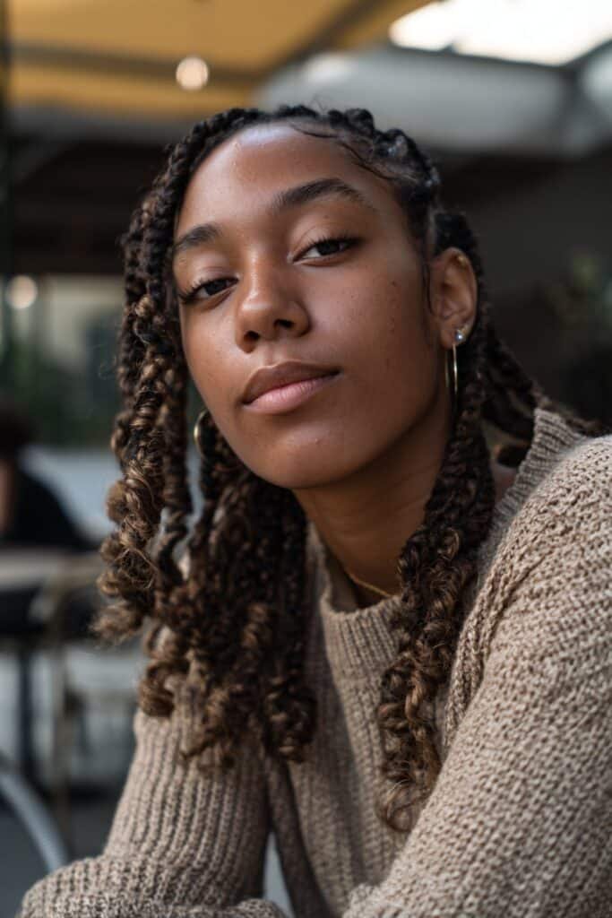Black woman wearing micro braids with soft curled tips.