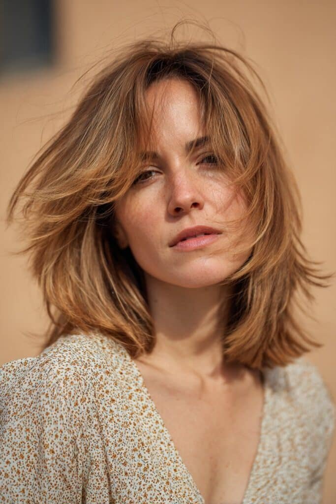 Shag cut with airy feathered ends and soft 70s feathered hair texture.