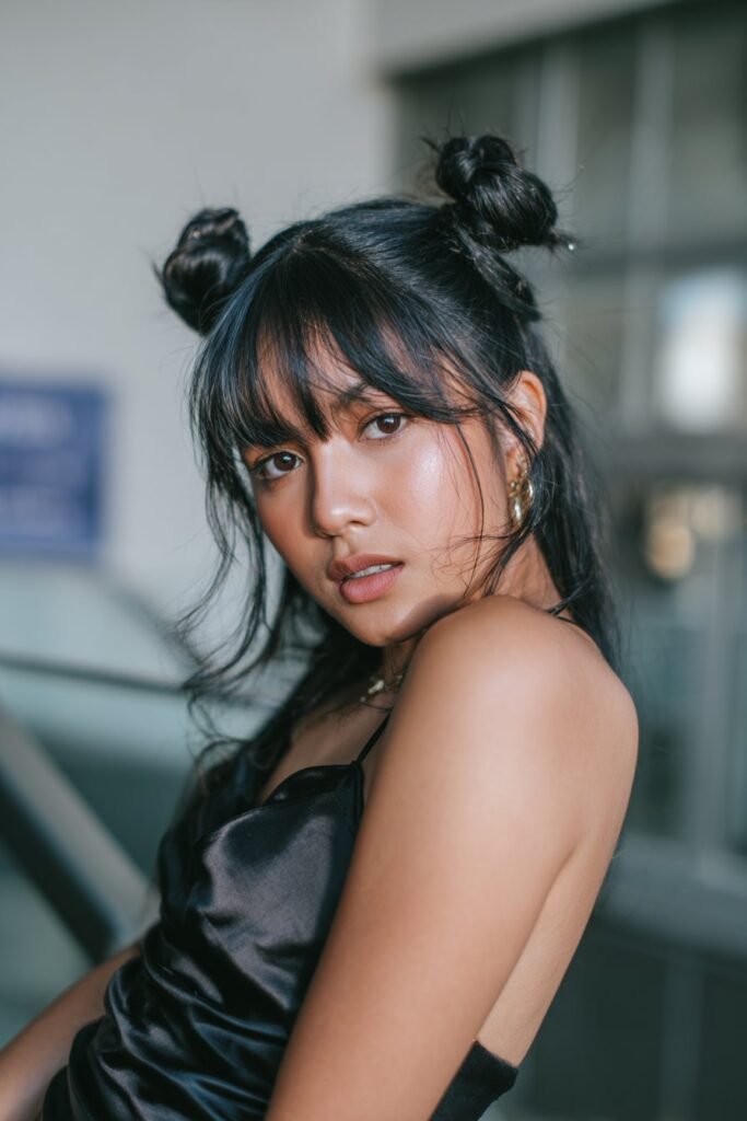 Teen girl showcasing playful space buns with sleek straight bangs for prom.