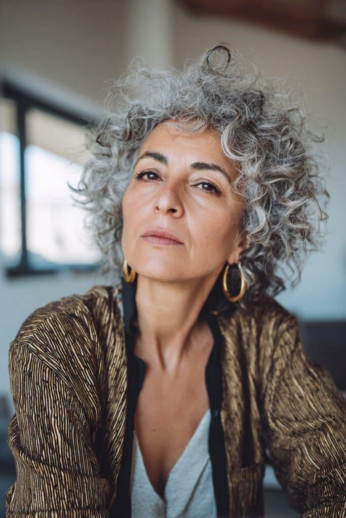 Woman with textured curly pixie and longer top layers.