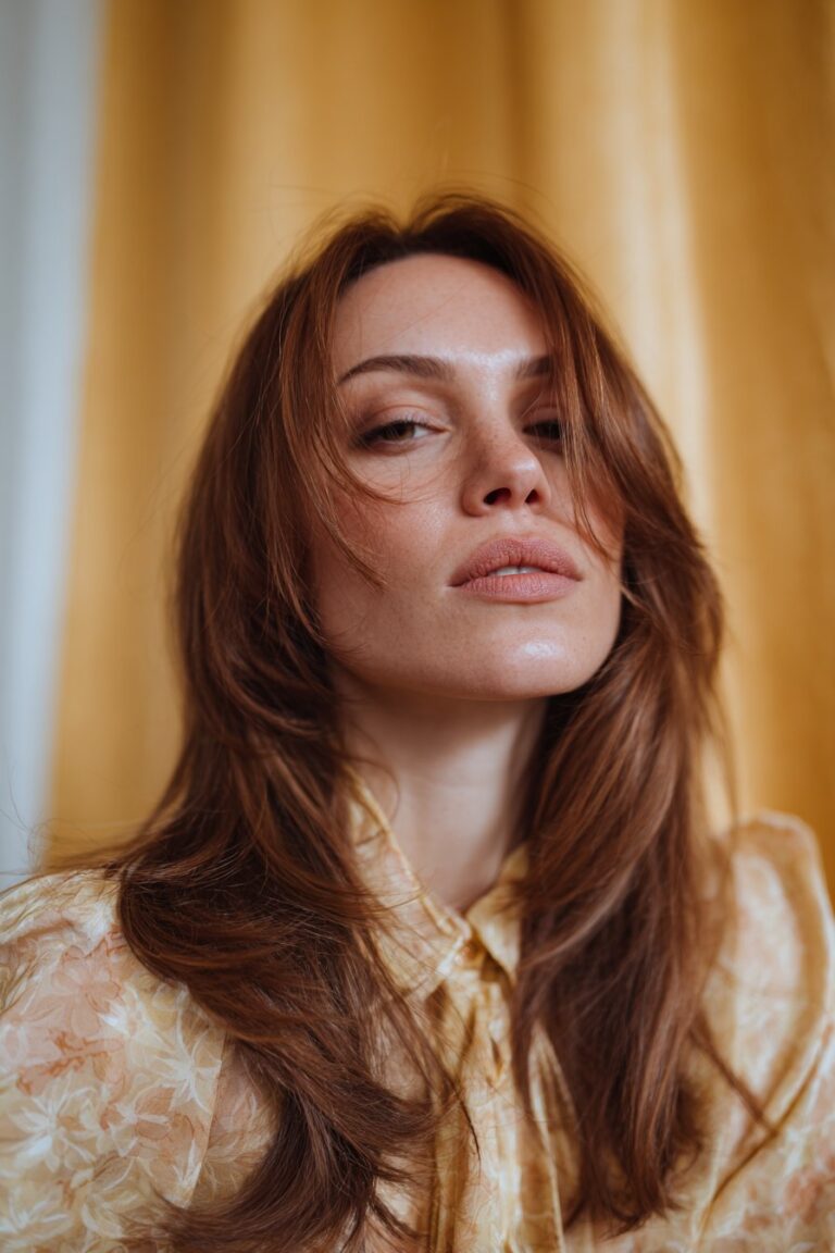 Winged side-swept 70s feathered hair flowing away from the face.