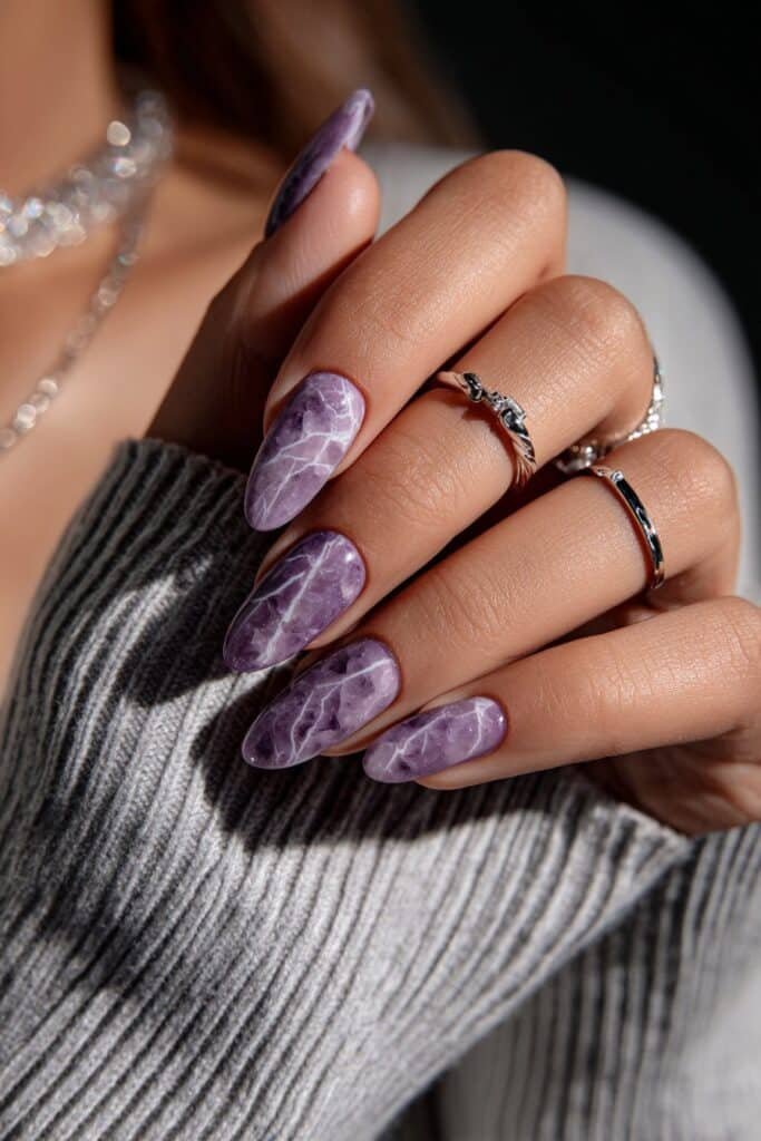 Almond nails with purple and white marble swirls and silver veining.