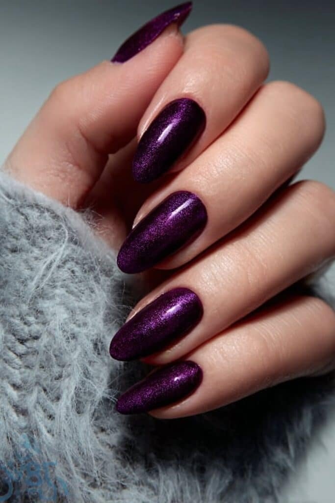 Deep plum velvet almond nails with rich dark purple matte texture, full hand with fingers curved inward.