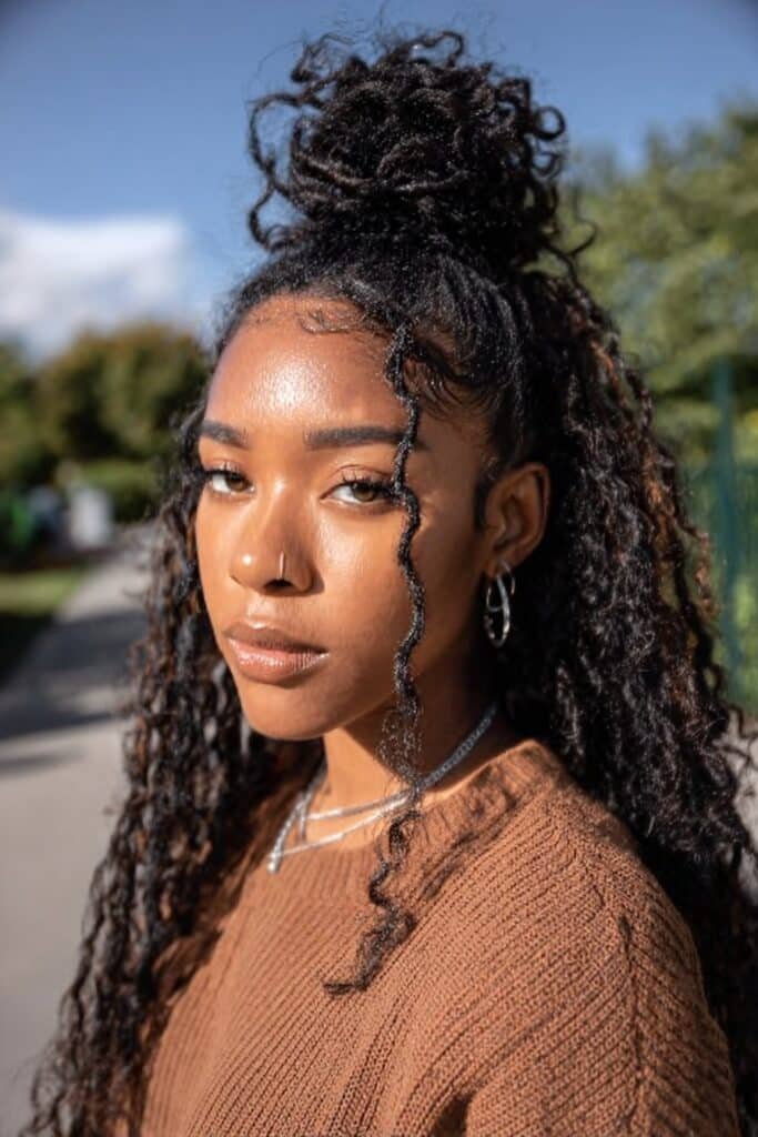 Black woman with half-up half-down wig updo and curly lengths.