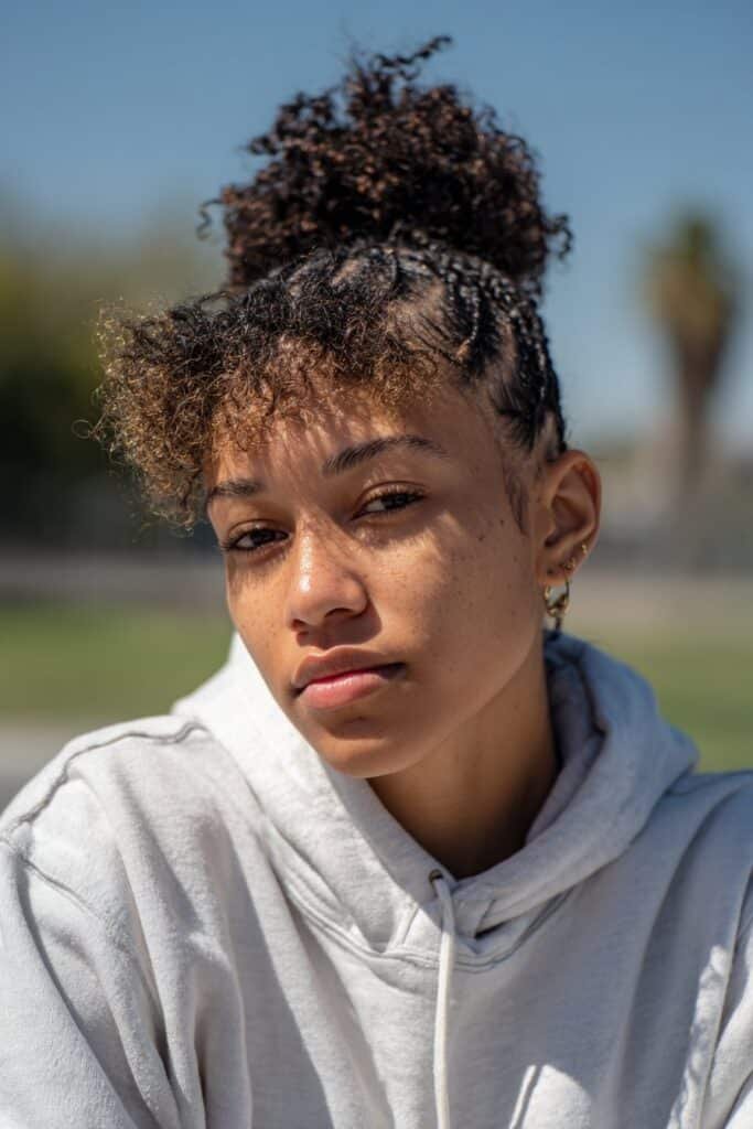 Black woman with high puff and braided face frame.