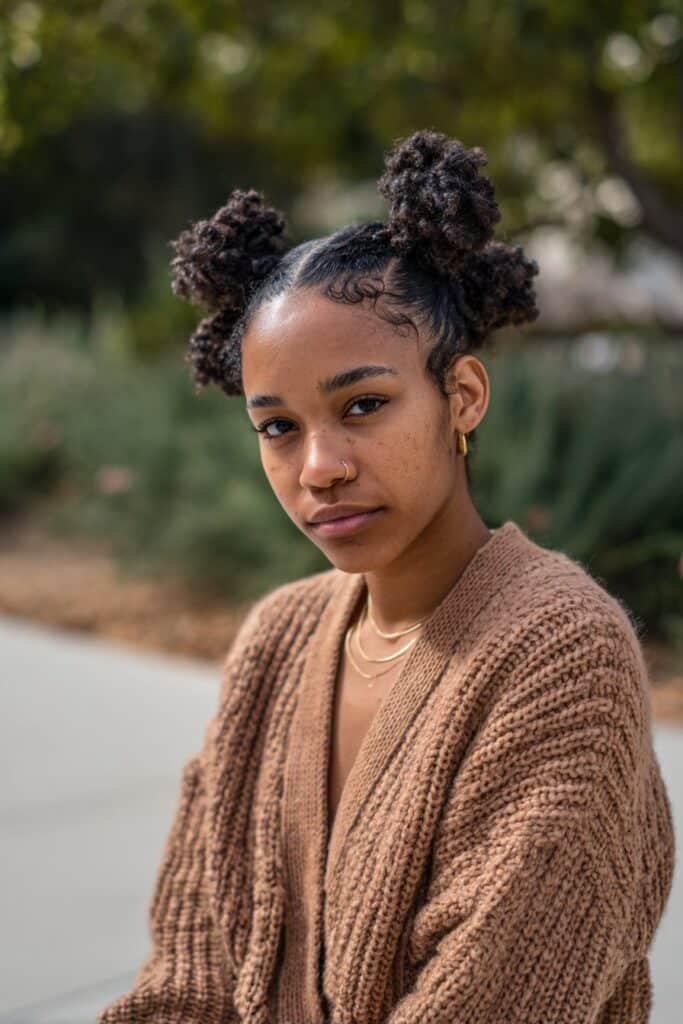 Black woman with two-strand twist bun, face-framing updos for Black hair.