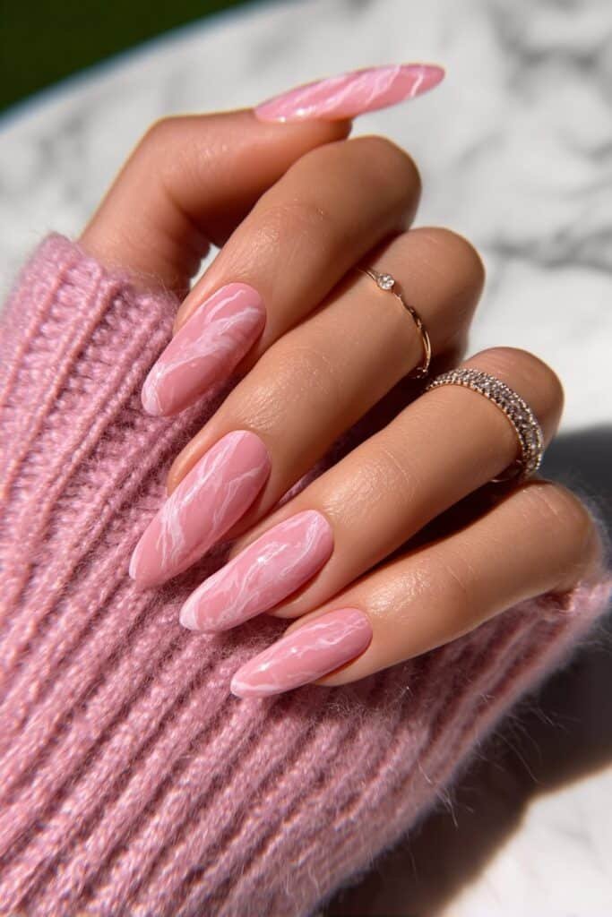 Blush pink almond nails with soft marble swirl patterns.