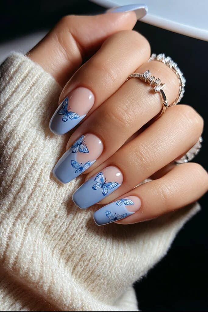 Blue nails with delicate butterfly designs and Blue accents.