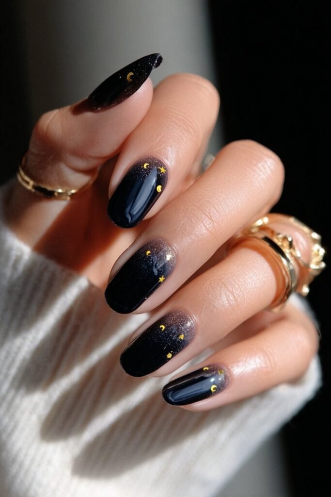 Celestial nails with gold moon and star designs on dark base