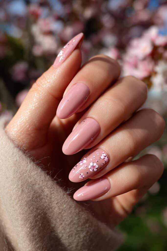 Soft pink nails with delicate cherry blossom flowers and tiny petals.
