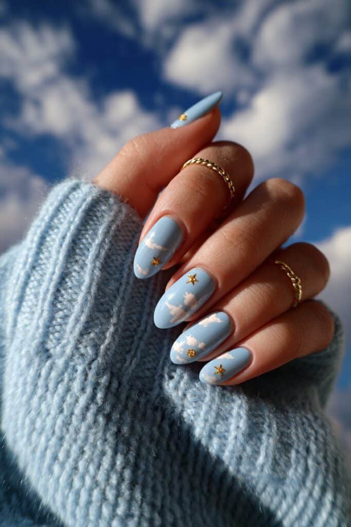 Sky blue nails with fluffy clouds and tiny gold star accents.