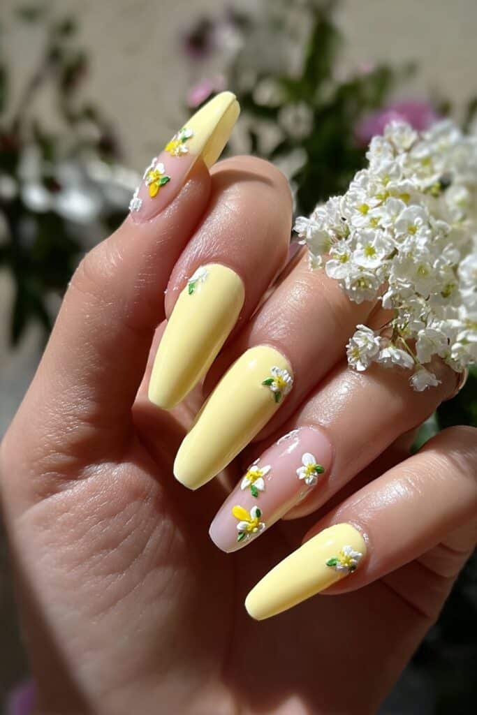 Pale yellow nails with delicate lemon blossoms and green leaves.