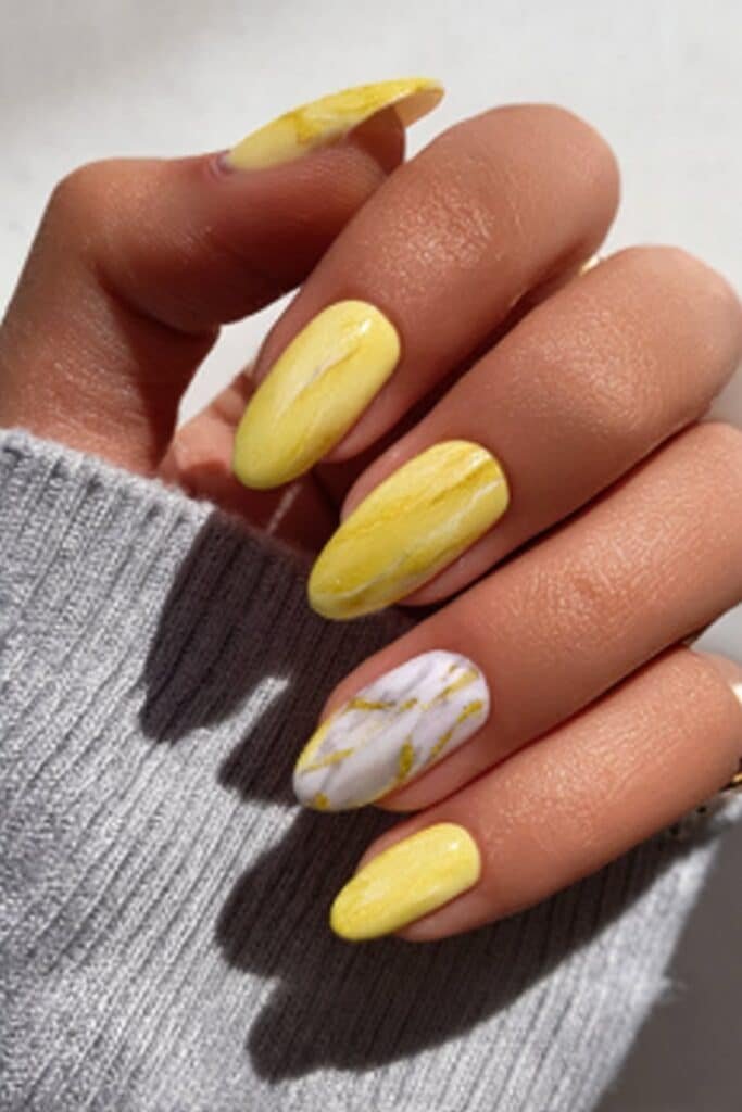 Yellow marble nails with white swirls and subtle gold veining.