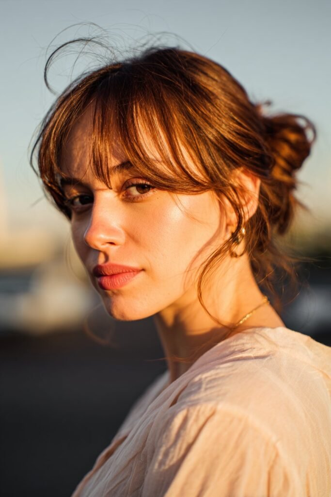romantic chignon low bun with wispy bangs, soft elegant hairstyle close-up