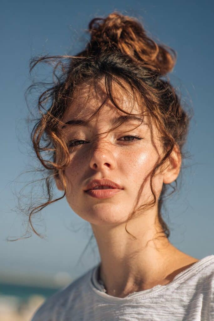 woman with textured low bun hairstyle, voluminous messy finish