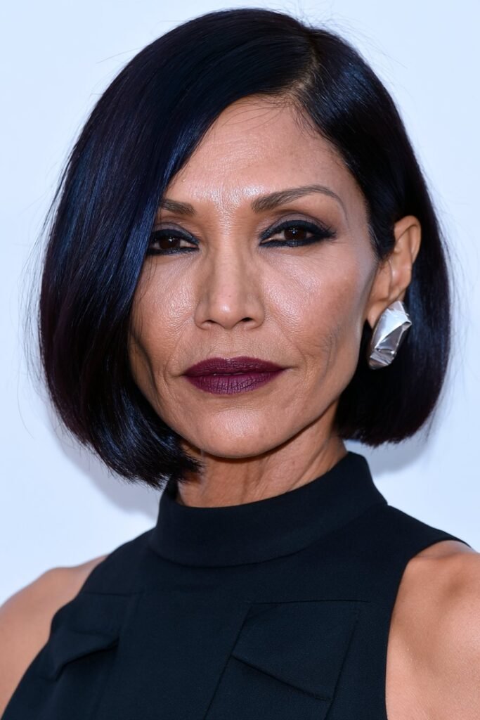 Elegant older woman with an asymmetrical layered bob in glossy espresso brunette.