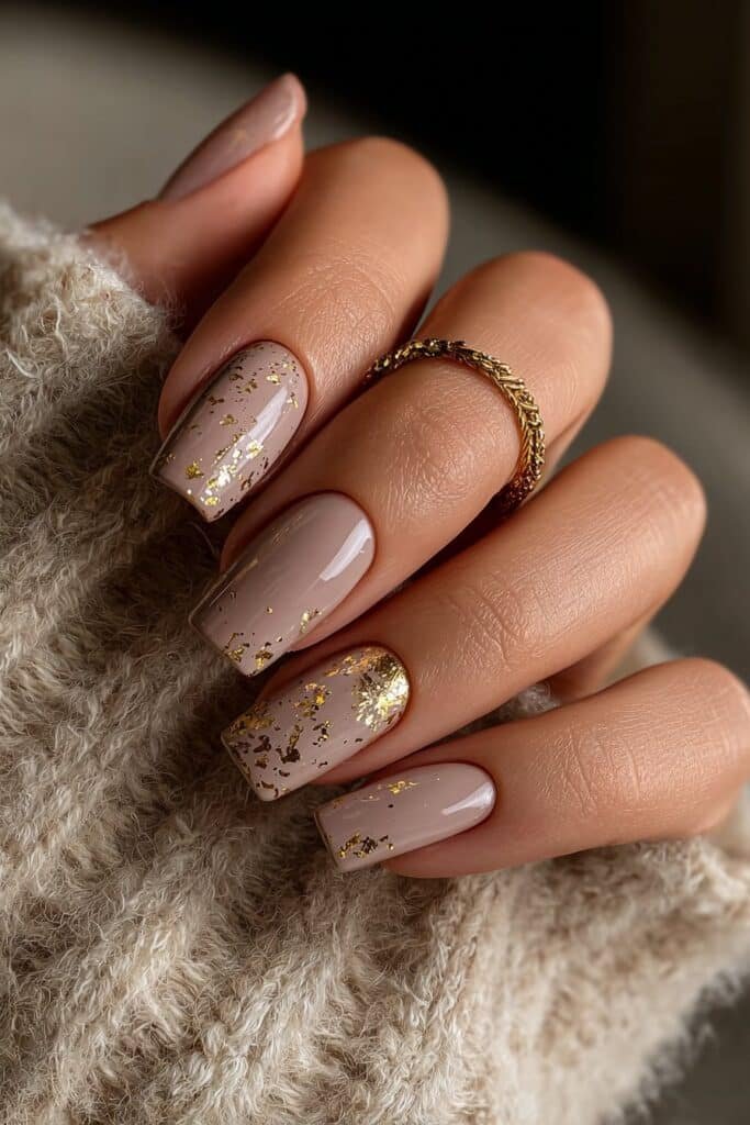 Soft begie square nails with scattered gold foil accents.