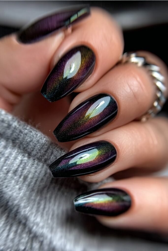 Dark holographic nails with shifting purple and green tones.