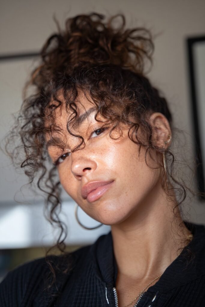 woman with messy curly bun, loose natural curls