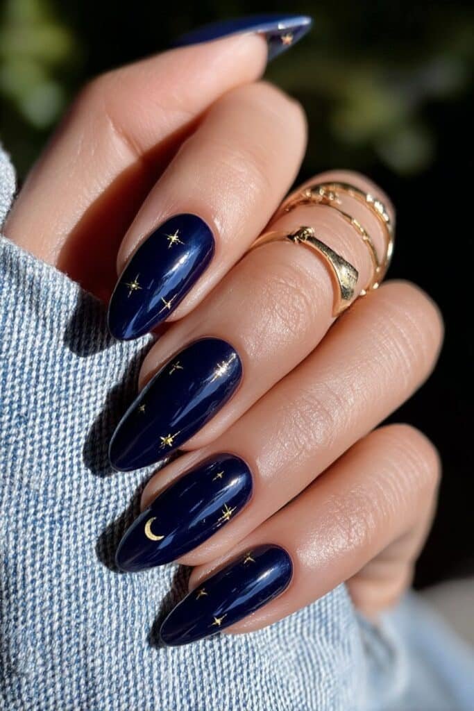 Navy blue nails with tiny gold star details and glossy shine.