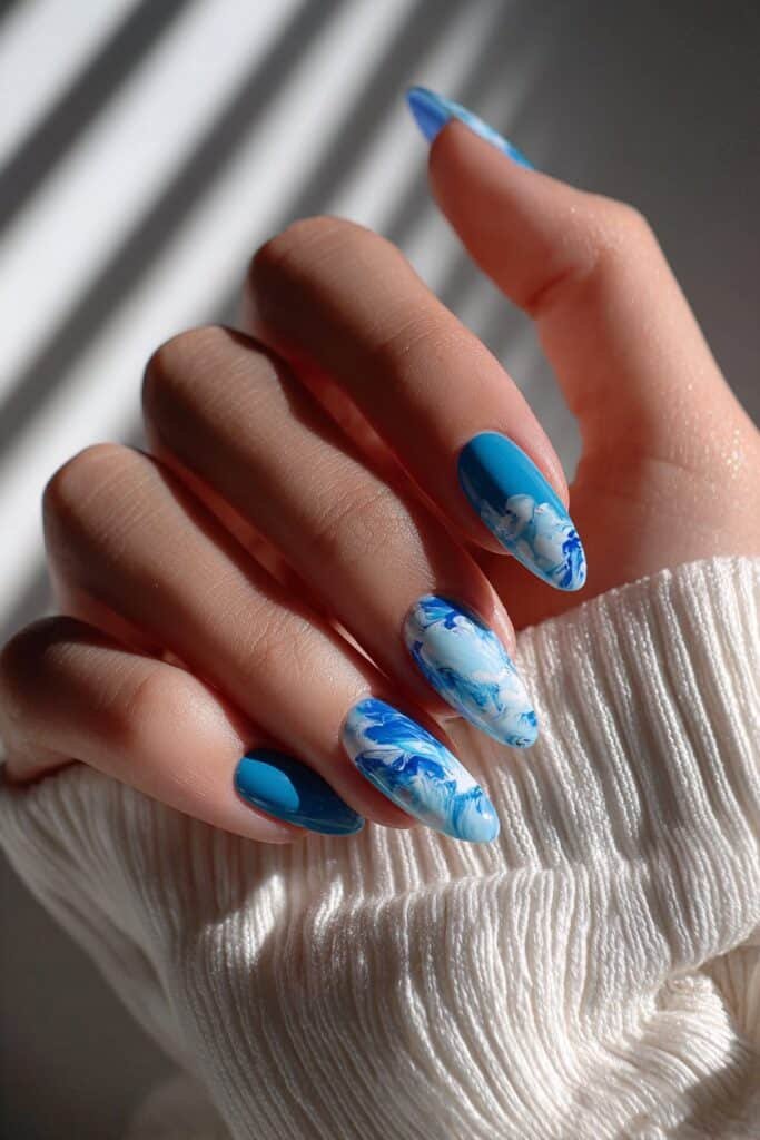 Blue and white nails with ocean wave swirl patterns.