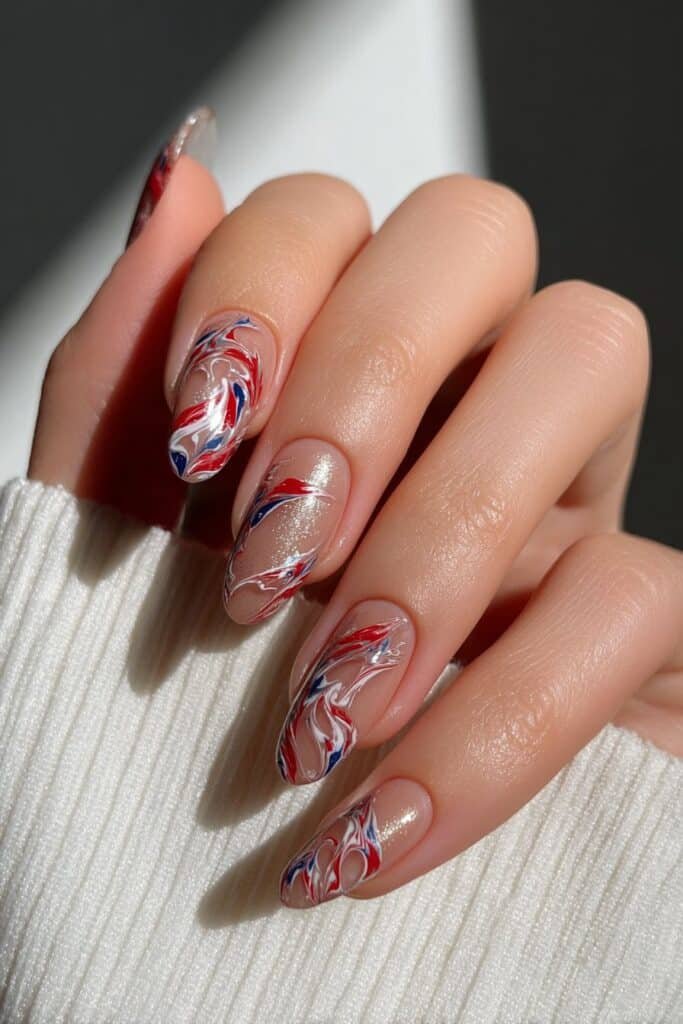 Marble patriotic nails blending red, blue, and white swirls.