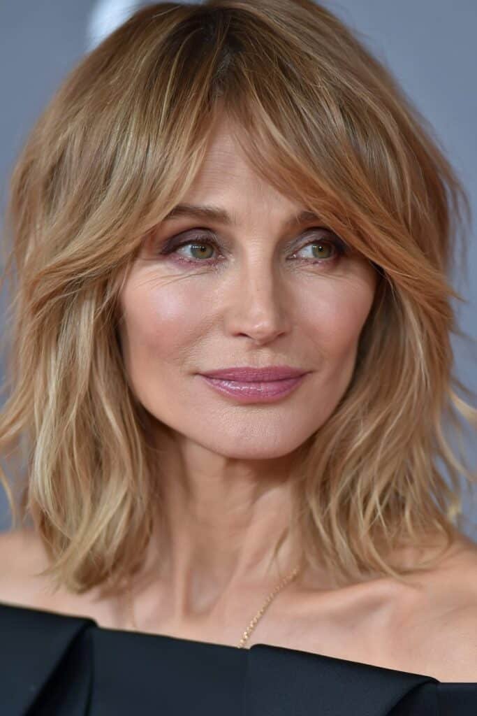 Older woman with a shoulder-length shag haircut and honey blonde layers.