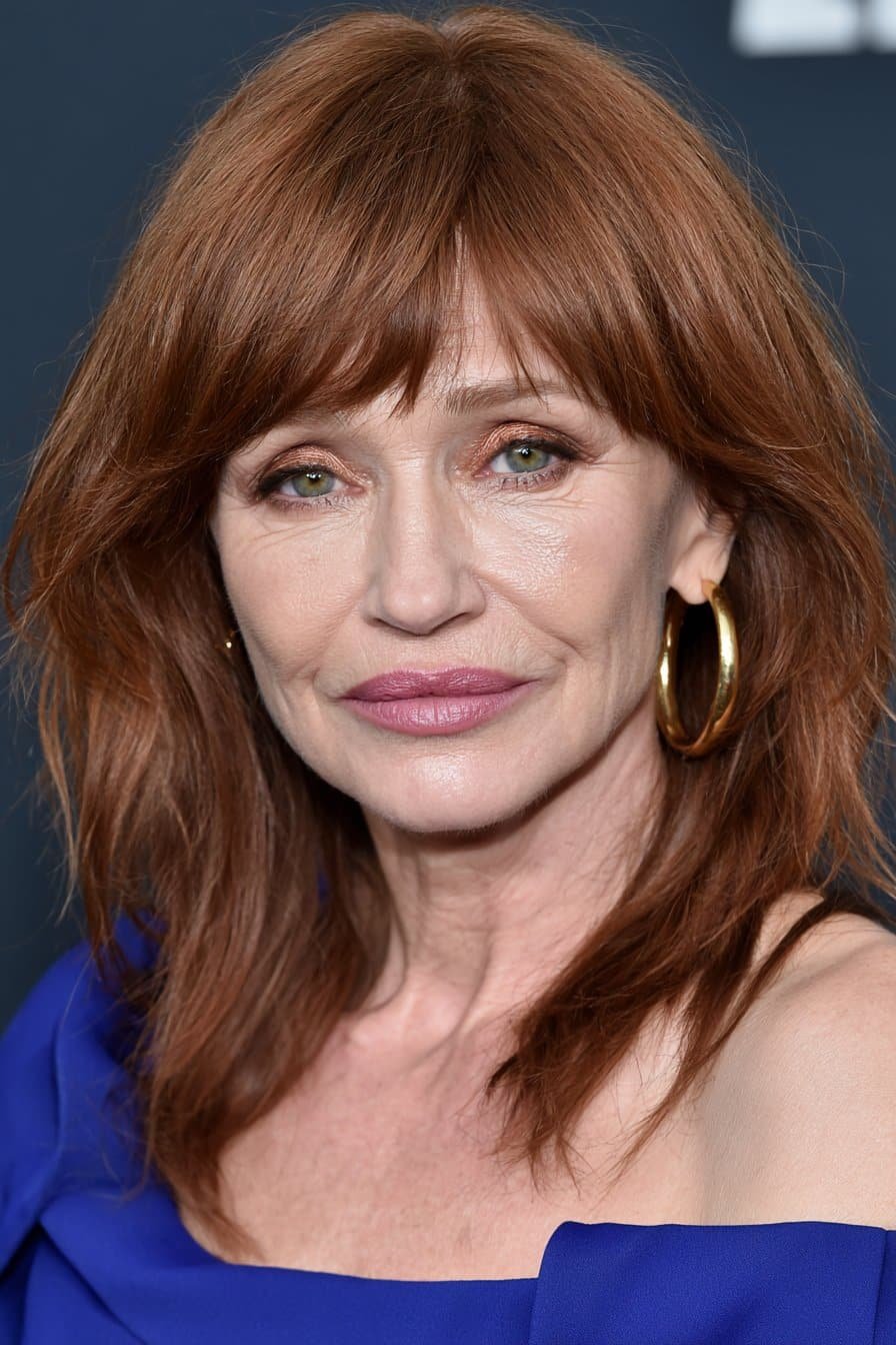 Woman over 60 with soft shaggy layers and a side-swept copper fringe.