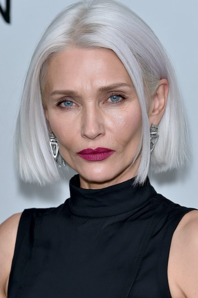 Sophisticated woman with a sleek chocolate brown blunt lob and bold red lips against a white studio backdrop.