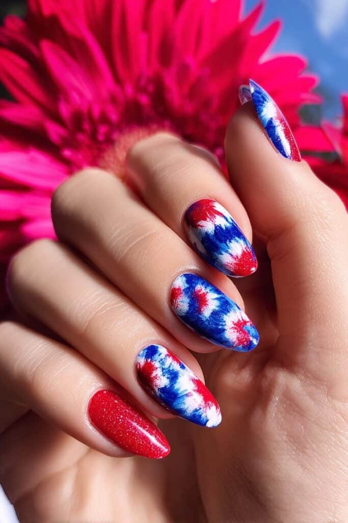 Patriotic tie-dye nails with red, white, and blue swirls.