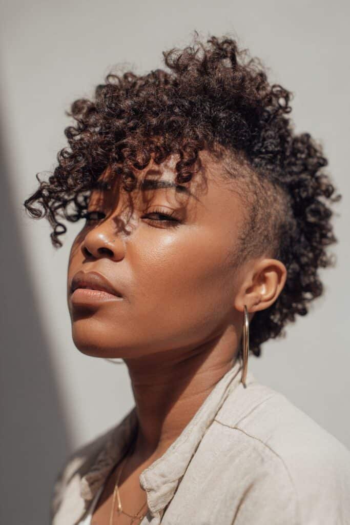 Black woman with a tapered cut and defined kinky curly crown.