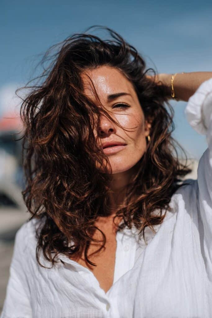 Woman wearing air-dried shoulder-length beach waves with natural movement.