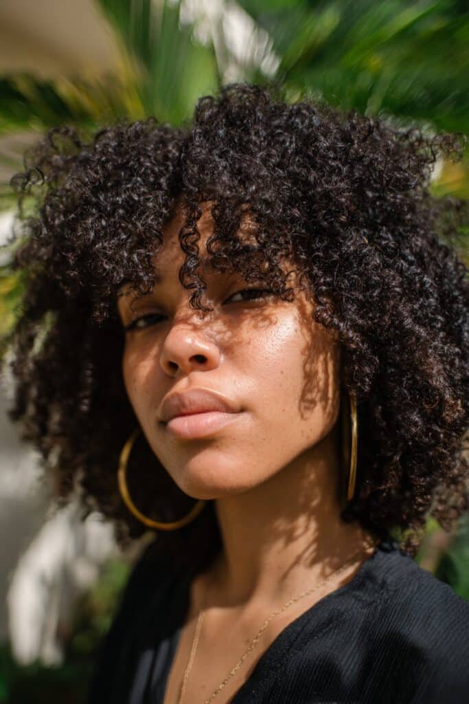 Black woman wearing faux locs blended with kinky curly texture.