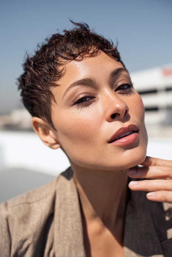 Woman with a finger wave pixie cut featuring perfectly laid baby hairs and intricate wave detailing on a rooftop terrace.