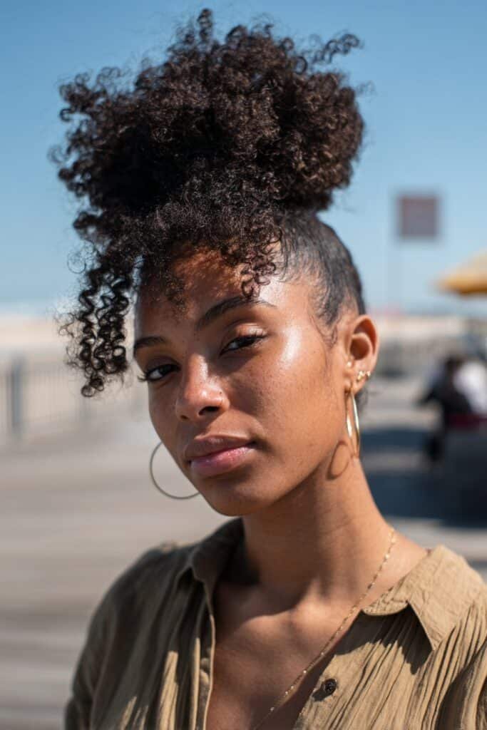 Black woman with a high puff featuring voluminous kinky curly hair.