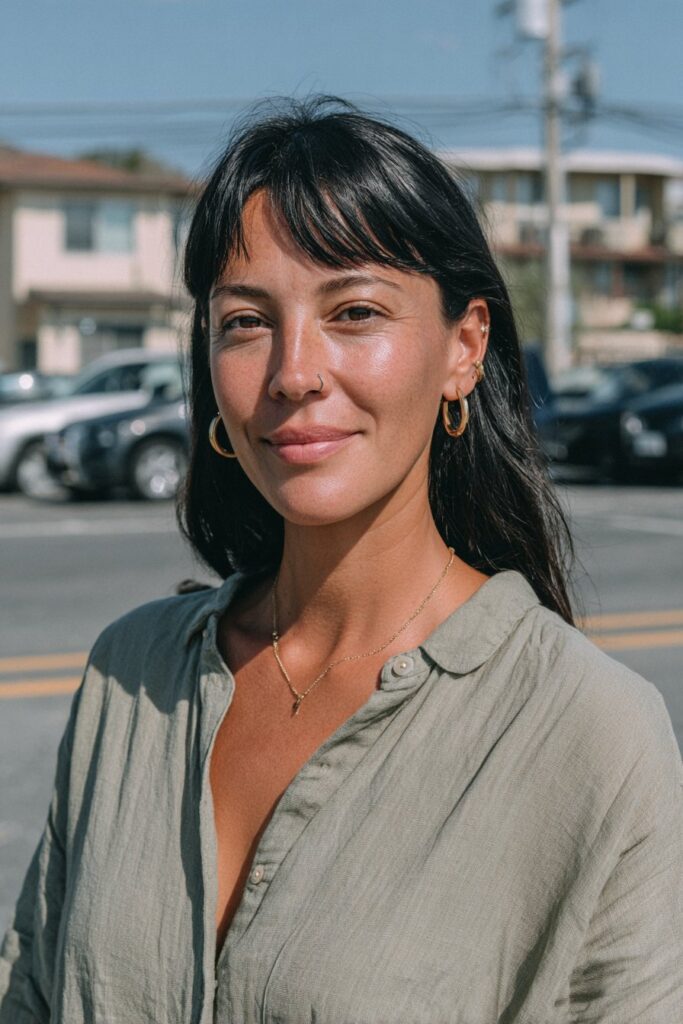 Woman over 40 with long jet black hair and bold micro bangs.
