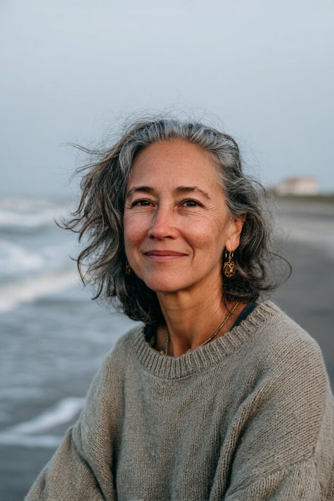 Older woman wearing a shoulder length shag with tousled salt and pepper layers.