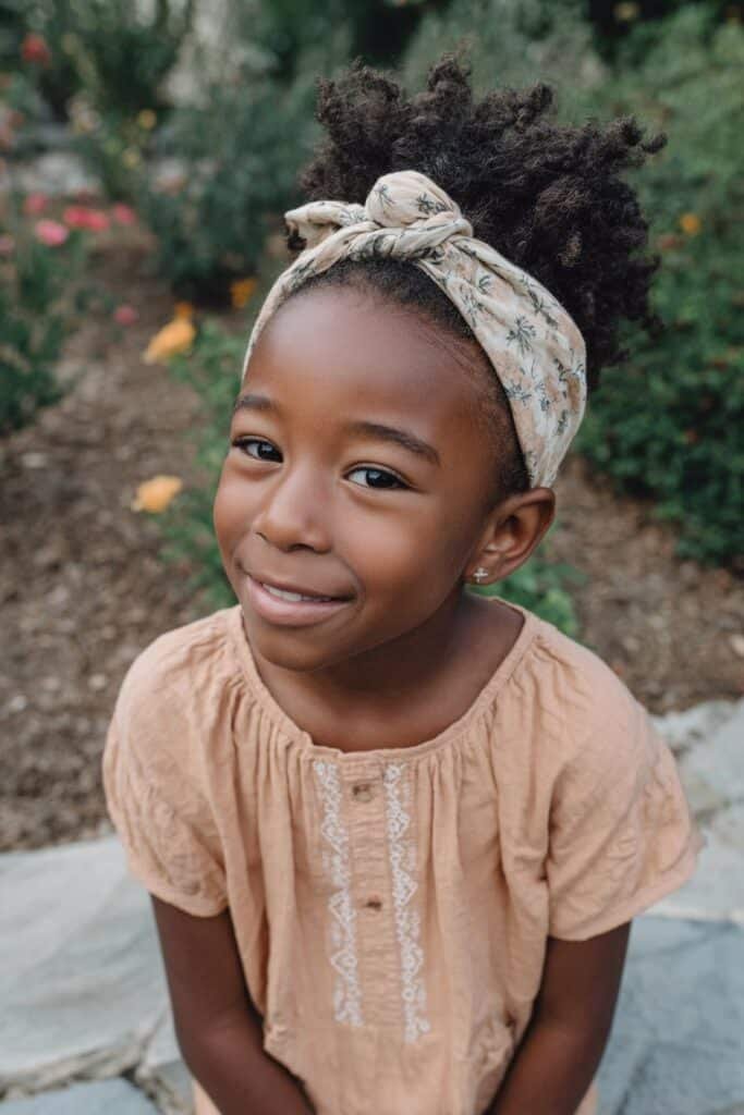 Black girl with a fluffy afro puff and floral headband