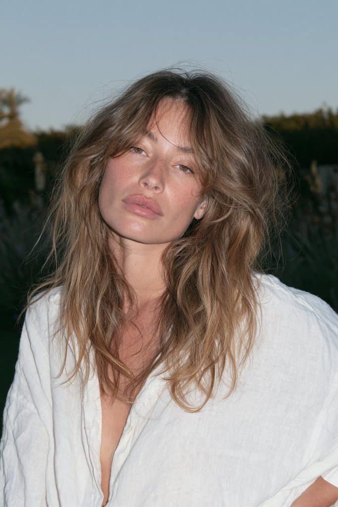 Young woman with a brunette jellyfish haircut and honey-caramel balayage lower layers.