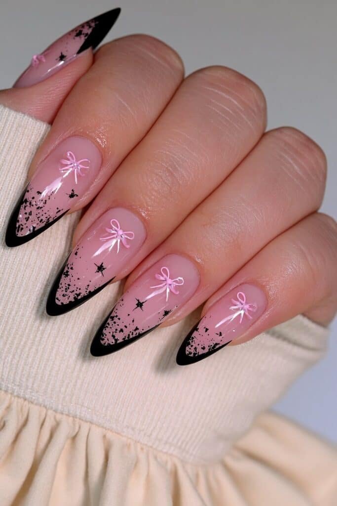 Sheer nude almond nails with black French tips and pink bow accents.