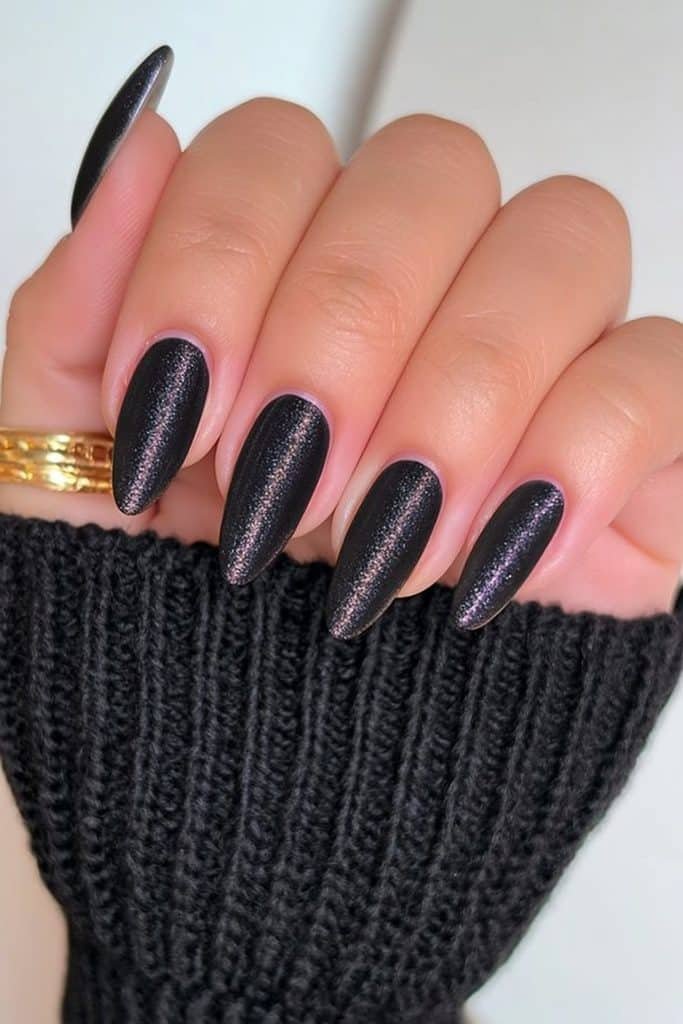 Short oval nails in black velvet with subtle silver cat-eye shimmer.
