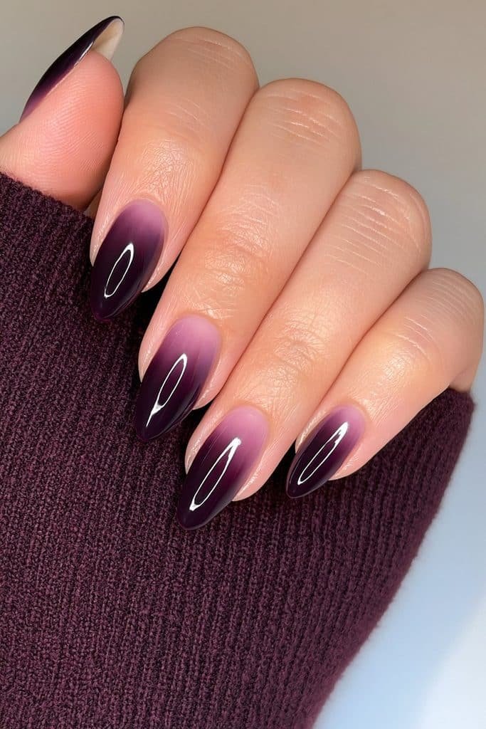 Short almond nails in rich blackened plum with a sleek glossy finish.