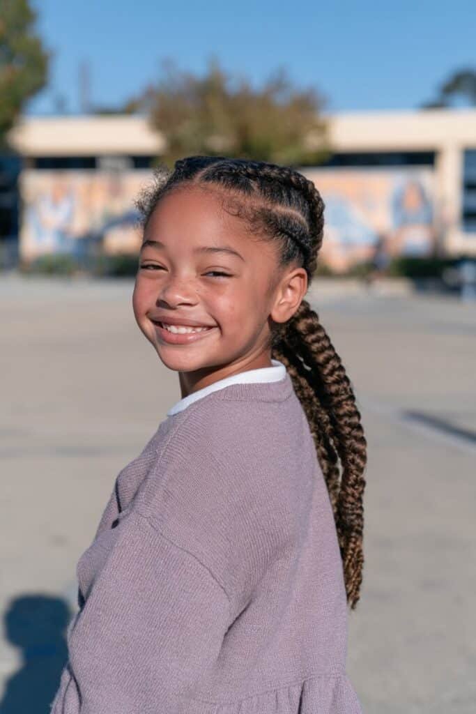 Young Black girl with a long braided ponytail and softly styled edges