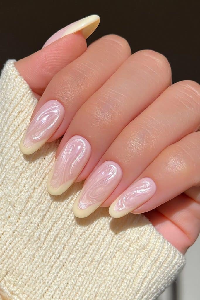 Nails in translucent buttery yellow with a pearlescent glazed chrome swirls finish.