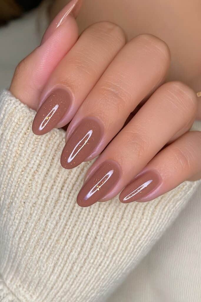 Short oval caramel brown nails with warm beige undertones and a smooth glossy finish.