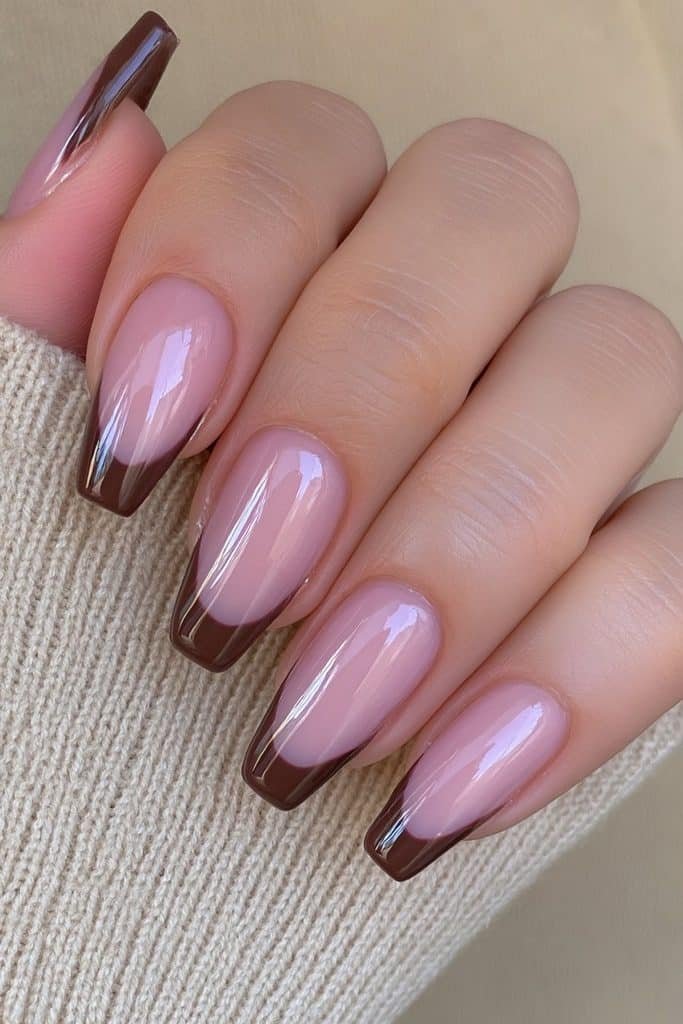 Short almond nails with sheer nude base and chocolate French tips